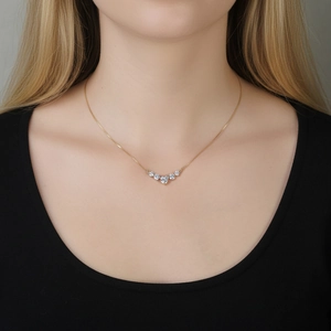 Close-up of sparkling moissanite smile necklace on model with five graduated gemstones