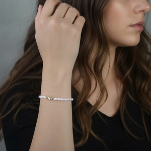 Elegante pulsera de perlas de plata S925 con un dije de corazón dorado al pulso