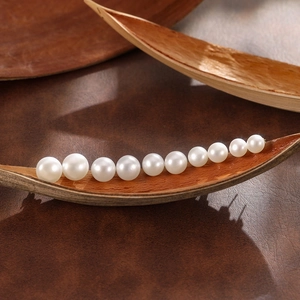 Eleganti orecchini di perle bianche con dimensioni sfumate su espositore in legno