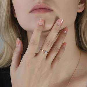 Bague croix dorée élégante avec pierres en moissanite micro-pavées sur un doigt