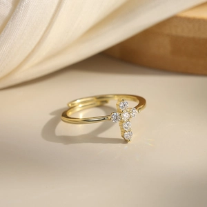 Bague croix dorée réglable ornée de moissanites sur un élégant tissu en soie crème