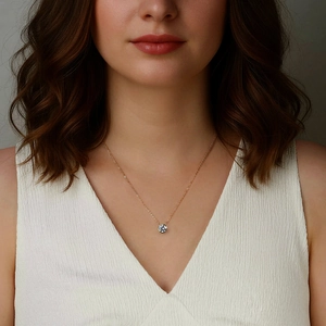 Dettaglio di una collana con ciondolo in moissanite dorata indossata da una modella in scollo a V