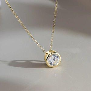Dettaglio della collana in moissanite dorata con ciondolo a lunetta rotonda ed effetto a stella