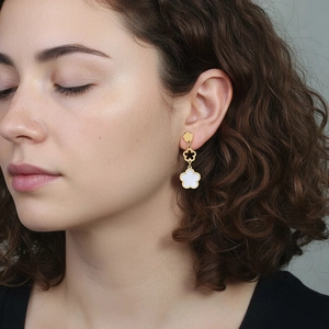 Dreistöckige goldene Blumenohrringe mit weißer Perlmutt-Einlage, am Model getragen