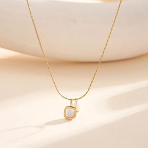 Elegante gouden slangenschakelketting met vierkante schelphanger en witte parel