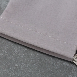 Bolsa de terciopelo gris para joyas con cordón sobre fondo de mármol oscuro