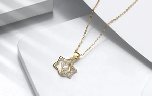 Close-up of gold star pendant necklace featuring shimmering pavé set white zircon stones