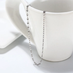 Primer plano de una cadena de plata de ley 925 sobre una taza de cerámica blanca pura