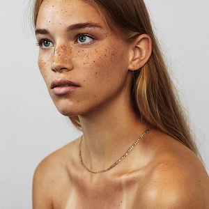 Chaîne Figaro classique plaquée or présentée sur un mannequin femme au style minimaliste