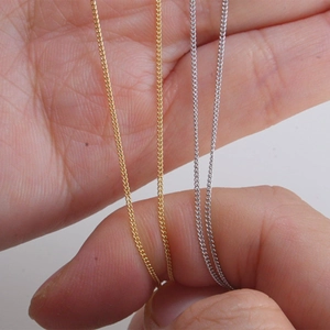 Detail of 925 silver and gold plated curb chain necklaces held in hand for size comparison