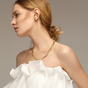 Close-up of a gold Figaro chain necklace and geometric ear clips on a female model