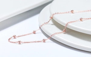 Makroaufnahme der S925 Sterlingsilber Roségold Perlenkette auf weißem Keramikteller