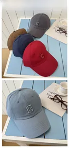 Détail de la lettre C brodée sur des casquettes en coton de couleurs variées