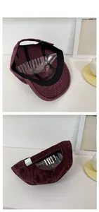 Detail view of burgundy corduroy baseball cap with adjustable metal buckle and strap