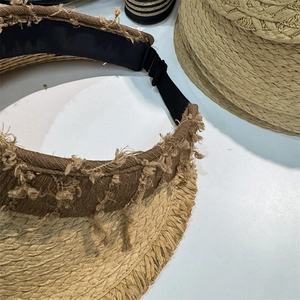 Close-up of woven straw sun hat brim with frayed edge detail and elastic band