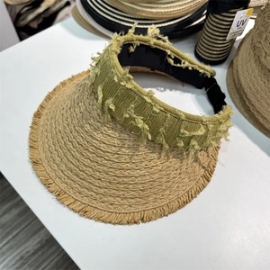 Detail of woven straw sun visor featuring frayed brim edges and a green textured band