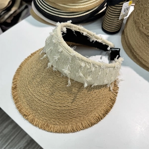 Detail of straw sun visor with frayed edges, cream ribbon and adjustable buckle