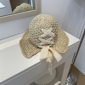 Straw sun hat with white lace bow and wavy brim for women on beach summer vacation