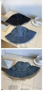 Detail of distressed denim bucket hat with raw edges and metallic stud embellishments