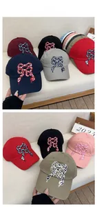 Detailed close-up of bow knot embroidery on multi-colored cotton baseball caps