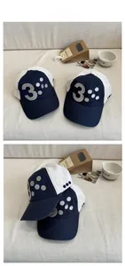 Detail of blue and white baseball cap featuring embroidered number 3 and polka dots