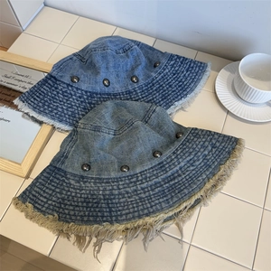 Distressed denim bucket hat with metal studs and frayed edges in blue washes