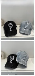 Close-up of distressed denim baseball caps with white spiral embroidery and worn-out details