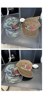 Detail of embroidered slogan on vintage camouflage and leopard print baseball caps
