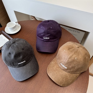 Drei Vintage-Baseballkappen aus PU-Leder in Grau, Lila und Braun auf einem Holztisch
