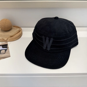 Retro black corduroy flat top cap with embroidered W logo on white decorative surface