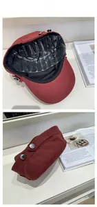Detail view of burgundy cotton flat top cap with silver side buttons and black inner lining
