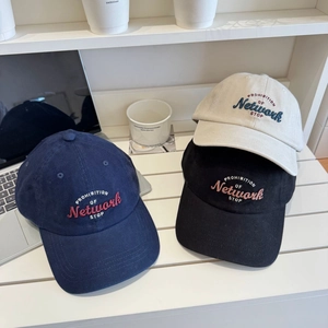 Stylish embroidered cotton baseball caps in navy, black and beige on a casual desktop