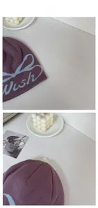Détail du bonnet en tricot violet avec lettrage Wish bleu clair et motifs brodés