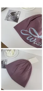 Détail du bonnet en tricot gris-violet avec jacquard de lettres bleu clair et étiquette
