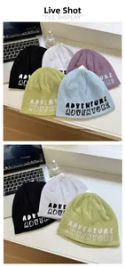 Flat lay of knit beanies in five colors featuring pixelated Adventure letter patterns