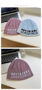 Flat lay of knit beanies in lilac and light blue featuring adventure letter patterns