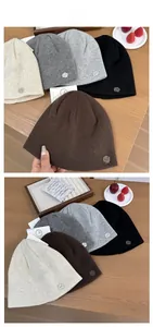 Flat lay detail showing five colors of ribbed knit beanies with metal logo on wood table