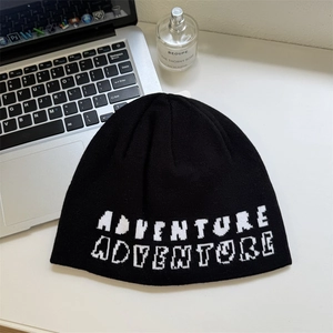 Black knit beanie featuring white pixelated Adventure text for winter street style