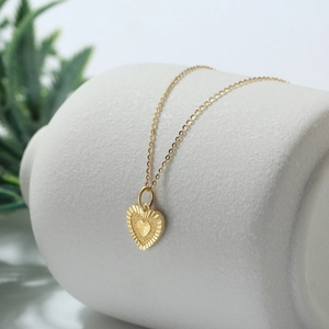 Detail eines 14K Gold-Herzanhängers mit Radialtextur und feiner Gliederkette