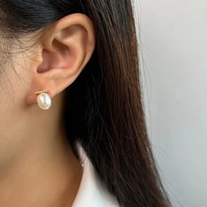 Detail view of a 925 silver earring featuring a baroque pearl and gold horizontal bar