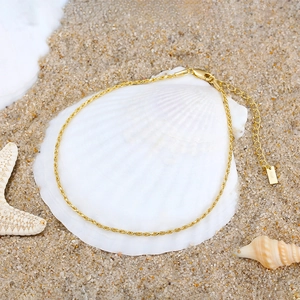 Elegant gold S925 sterling silver rope anklet with shell and starfish on a beach