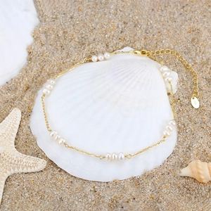 Elegant S925 sterling silver gold anklet with pearls on a beach seashell background
