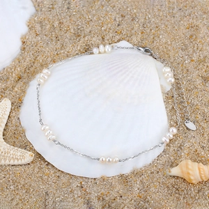 Detail of S925 sterling silver anklet with pearls on a decorative white seashell background
