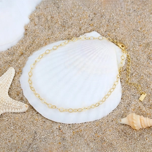 S925 sterling silver diamond chain anklet in gold finish on seashell and beach background
