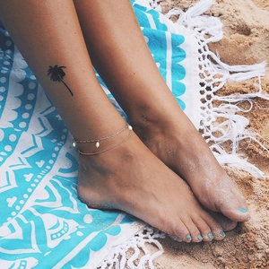 Minimalist double layer gold anklet with white pearls on a beach vacation setting