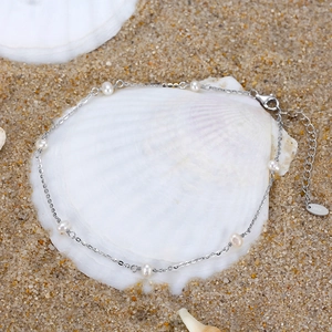 Detail of S925 sterling silver anklet with pearls on a white shell at the beach
