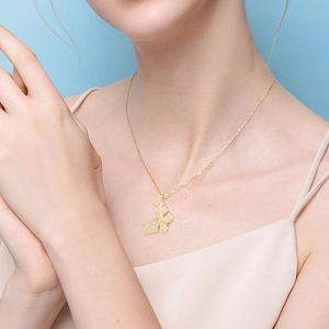 Elegant gold butterfly pendant necklace with crystal wings worn by a model in pink dress