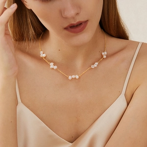 Elegante collana a catena dorata con perle barocche indossata da una modella stile minimal