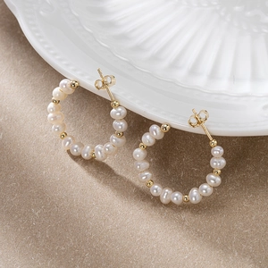 Elegant 925 silver C-shape earrings with white pearls and gold beads on a ceramic tray
