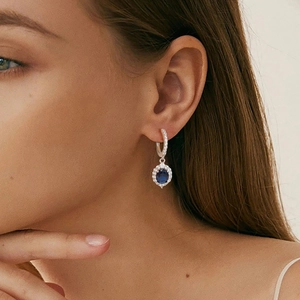 Detail of luxury S925 silver earrings with blue sapphire and pavé-set zircons on a model